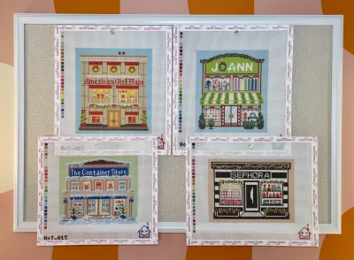 Village Expansion Series card artwork: American Girl Place, JOANN, The Container Store, and Sephora needlepoint storefronts